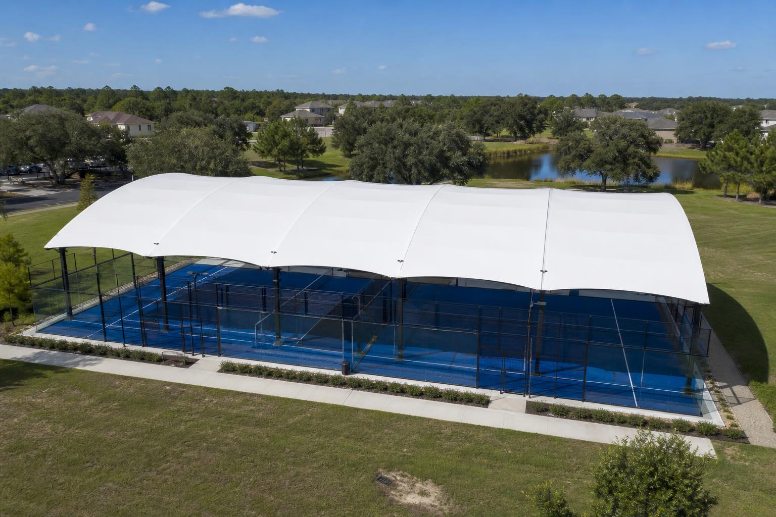 Aerial view of outdoor padel courts with white canopies at sunset